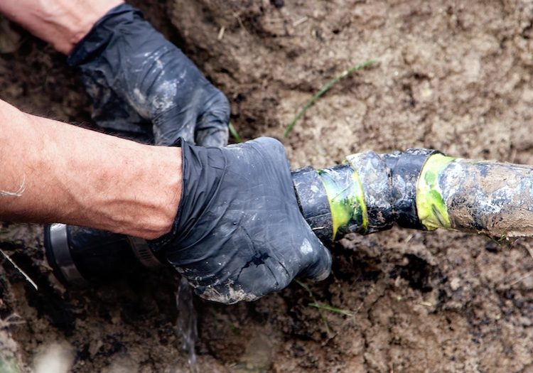 Gloved hands holding septic hose to perform emergency septic pump out in Charlotte County Florida